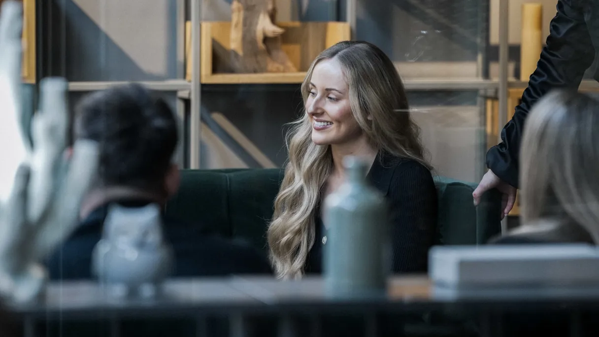 A woman with long hair smiling while seated in a modern café