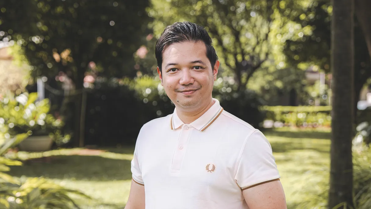 Man standing in a garden wearing a polo shirt and jeans