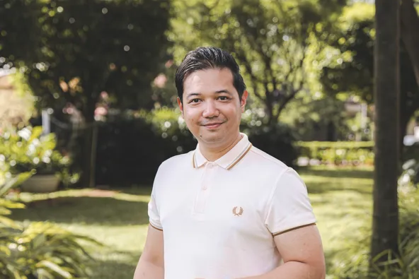 Man standing in a garden wearing a polo shirt and jeans