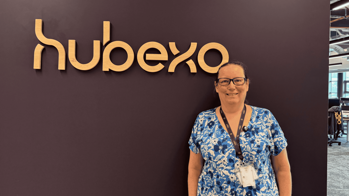 Person standing next to a "hubexa" sign on a purple wall