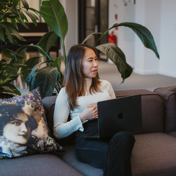 Two people sitting on a couch with laptops in a modern office setting